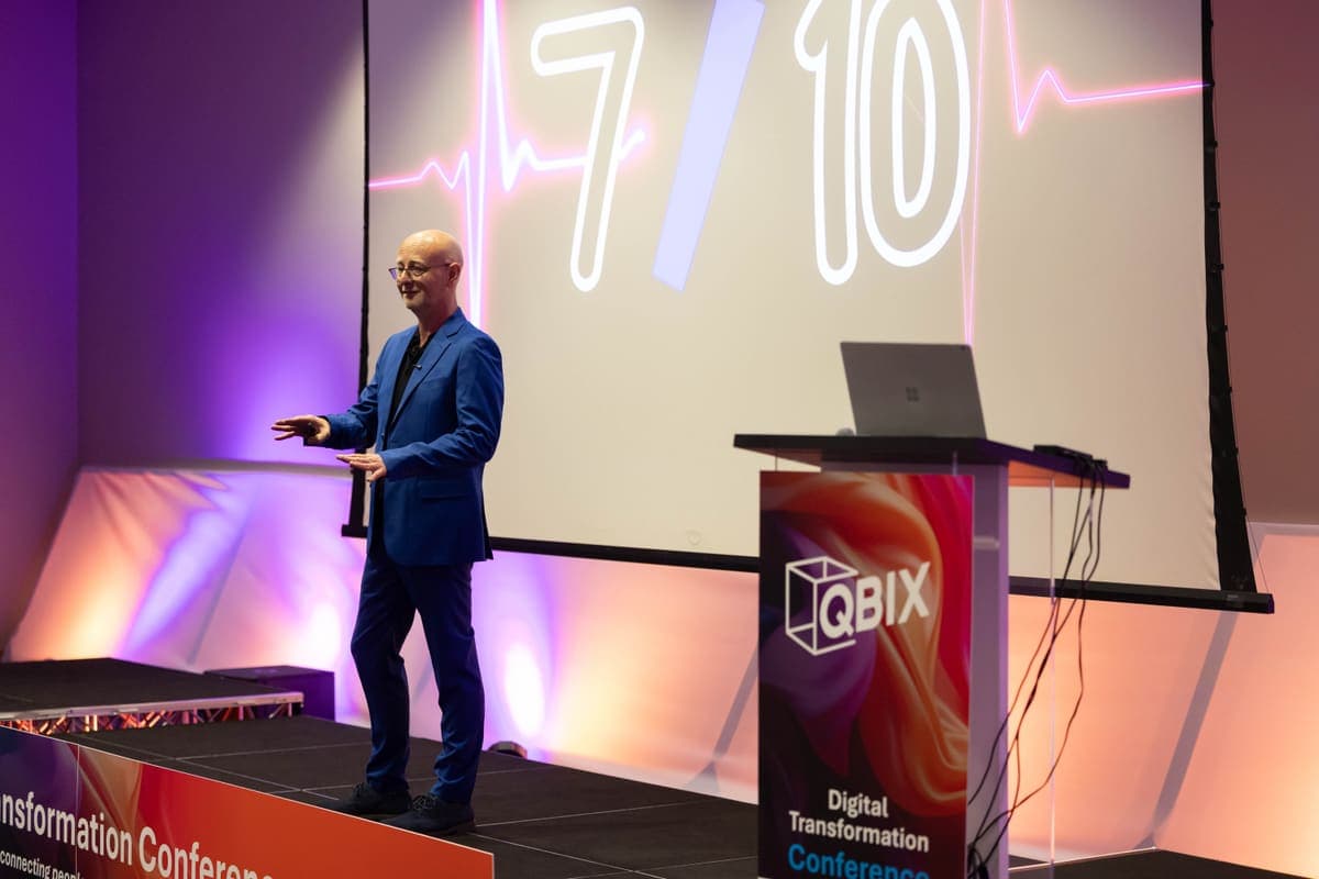 Andy Jarvis on stage beside a keynote data slide